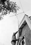 831058 Afbeelding van het bevestigen van een televisieantenne aan de zijgevel van een woning te Nieuwersluis (gemeente ...